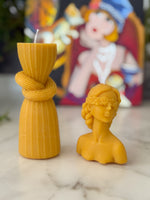 Balmumu tanrıça büstü ve sütun mum seti sanat tablosu önünde
